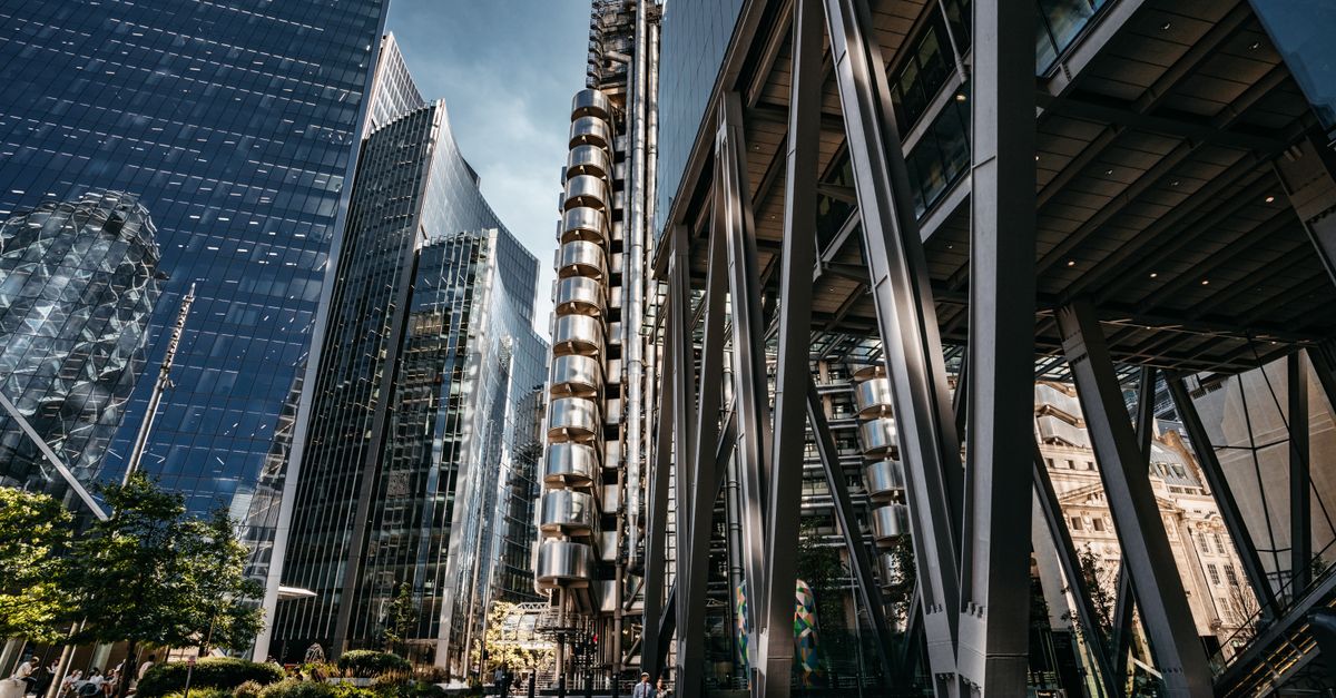 A bustling street view of modern skyscrapers in London's financial district with people walking below.